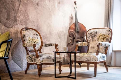 a room with two chairs and a table and a violin at Hotel Wieser in Campo di Trens