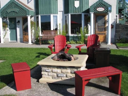 un cane che dorme in un focolare con due sedie rosse di Hotel Le Pionnier a Tadoussac