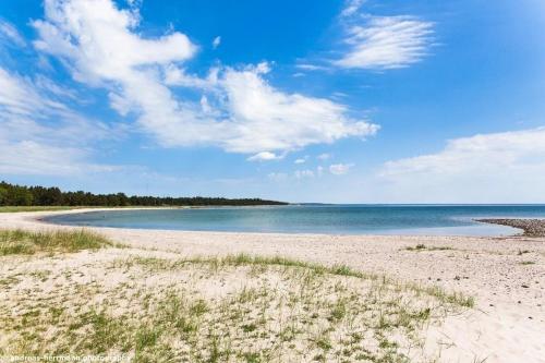 une plage de sable avec l'océan en arrière-plan dans l'établissement Großes Ferienhaus auf Gotland 700 Meter zum Meer, à Ljugarn