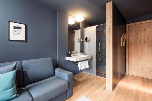 - un salon avec un canapé bleu et un lavabo dans l'établissement Hotel Lamm, à Castelrotto