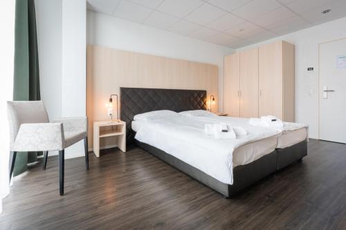 a bedroom with a large white bed and a chair at Los Lorentes Apartments Bern Airport in Belp