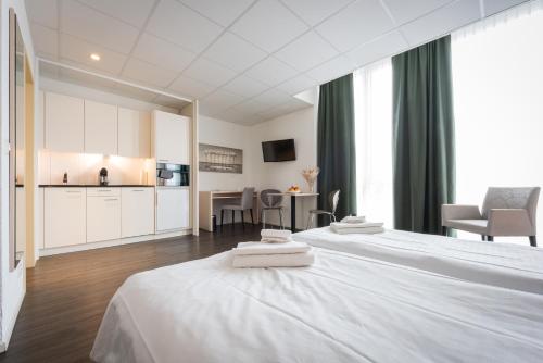 a hotel room with two beds and a kitchen at Los Lorentes Apartments Bern Airport in Belp