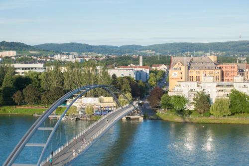 een brug over een rivier met een groep mensen erop bij Maximilian Hotel & Apartments Weil am Rhein / Basel in Weil am Rhein