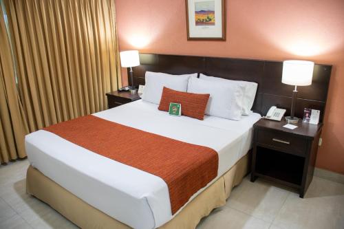 1 cama grande en una habitación de hotel con 2 lámparas en Hotel Arizona Suites Cúcuta, en Cúcuta