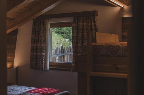 ein Schlafzimmer mit einem Fenster mit Blick auf einen Zaun in der Unterkunft Rifugio Lago Malghette in Madonna di Campiglio