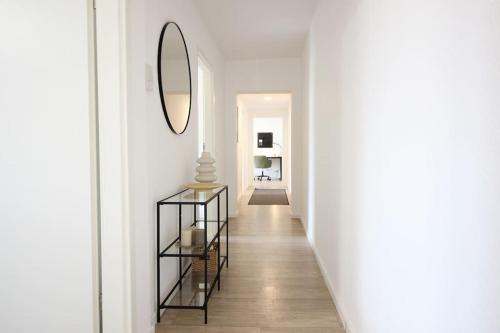 un corridoio con pareti bianche e uno specchio sul muro di Blossfeld-Apartments XL-Ferienwohnung Jena Zentrum, 2 Schlafzimmer, W-Lan, Waschtrockner, Smart-TV a Jena