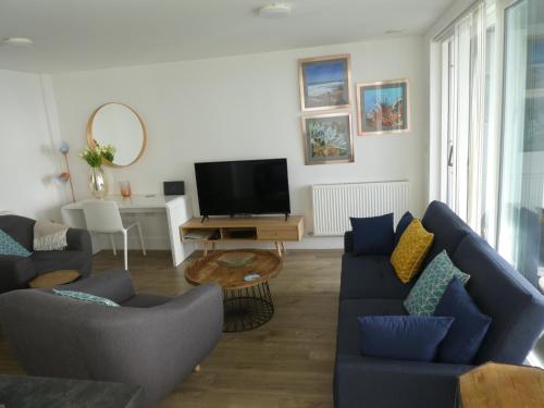 ein Wohnzimmer mit blauen Sofas und einem TV in der Unterkunft Seaview West Coast in Bournemouth