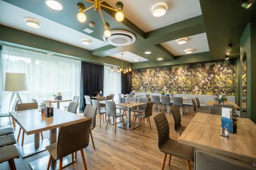 ein Restaurant mit Tischen und Stühlen und eine Wand mit Pflanzen in der Unterkunft Hotel & Spa Trzy Wyspy in Świnoujście