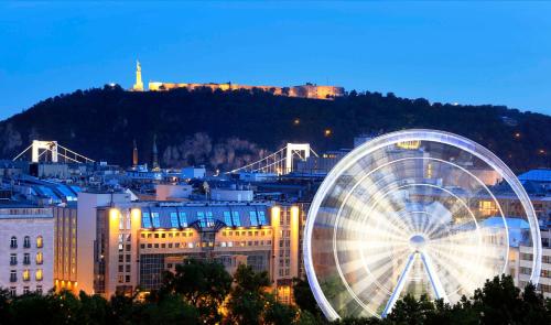 Una noria delante de una ciudad por la noche en Kempinski Hotel Corvinus Budapest, en Budapest