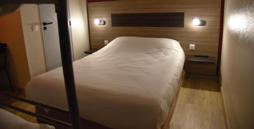 a small bedroom with a white bed in it at Hotel du Triangle in Talange