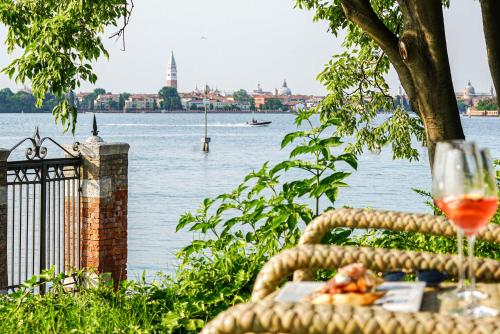 een glas wijn op een tafel naast het water bij San Clemente Palace Kempinski Venice in Venetië