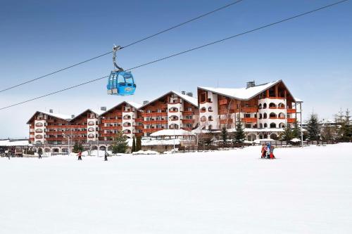 einen Skilift vor einem Gebäude im Schnee in der Unterkunft Kempinski Hotel Grand Arena Bansko in Bansko