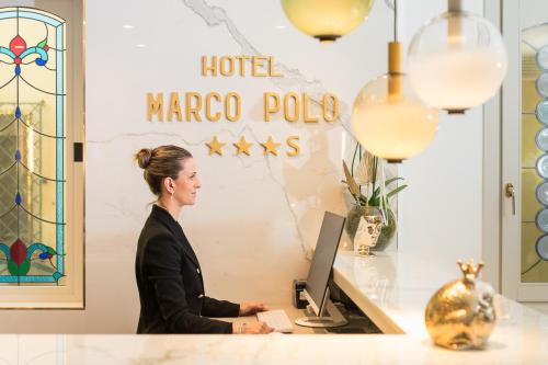 uma mulher sentada numa secretária com um computador em Hotel Marco Polo em Lido di Jesolo