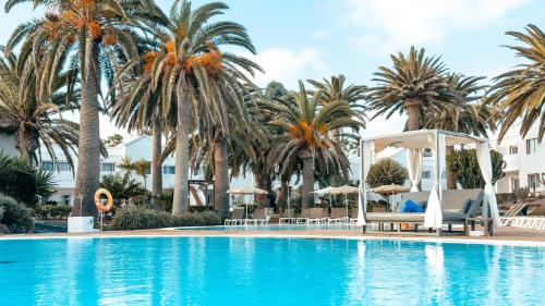 een zwembad met palmbomen en een prieel bij Labranda Corralejo Village in Corralejo