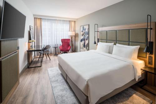 ein Hotelzimmer mit einem großen Bett und einem roten Stuhl in der Unterkunft Radisson Blu Hotel, Hamburg Airport in Hamburg