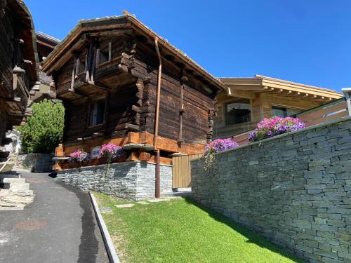 ein großes Holzhaus mit einer Steinmauer in der Unterkunft Chalet Coral und Zermatter Stadel mit Sauna in Zermatt