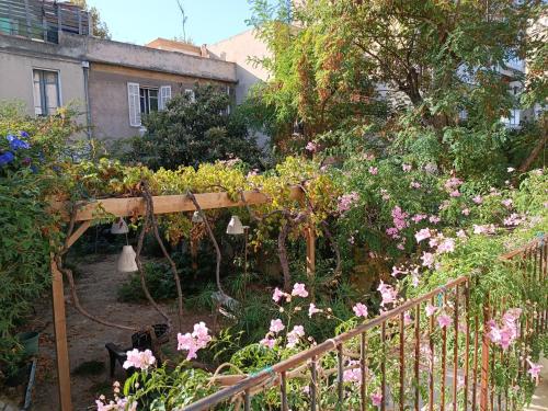 Chambre d'hôtes 2 pers - Maison avec jardin et terrasse près de la Friche de la Belle de mai في مارسيليا: حديقة بها ورد وردي وبيرغولا خشبي