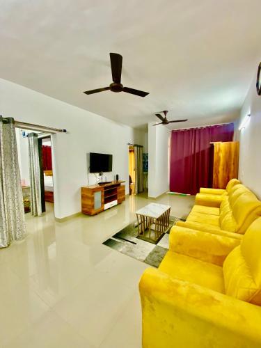 uma sala de estar com um sofá amarelo e uma televisão em 2 BHK AC Apartment em Pune