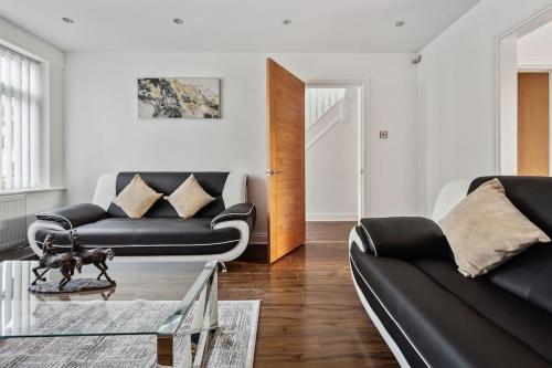 uma sala de estar com dois sofás pretos e uma mesa em house in Heald Green village em Manchester