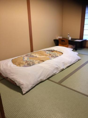 un letto con coperta sul pavimento in una stanza di Ryokan Kousen Kazeya Group a Nara