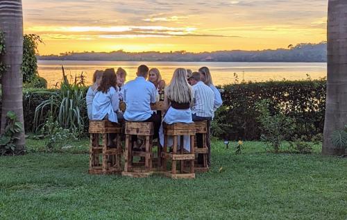 um grupo de pessoas sentadas num banco a ver o pôr-do-sol em Oslo Gardens Bed & Breakfast em Entebbe