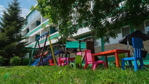 un mucchio di sedie colorate nell'erba di fronte a un edificio di Hotel Decebal Estival Neptun a Neptun