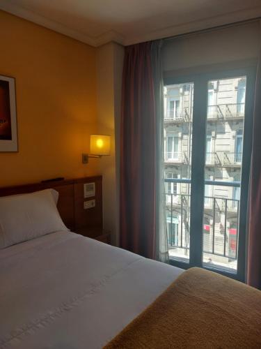 ein Schlafzimmer mit einem Bett und einem großen Fenster in der Unterkunft U Hotel Ogalia Vigo in Vigo