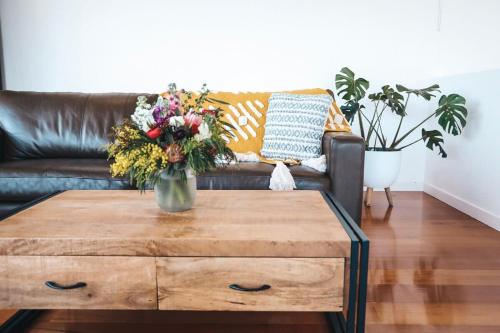 - un salon avec un canapé et une table ornée d'un vase de fleurs dans l'établissement Pitcher Vista, à Port Campbell