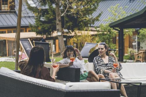 três mulheres sentadas em cadeiras segurando copos de vinho em Łubinowe Wzgórze Dom II em Nałęczów