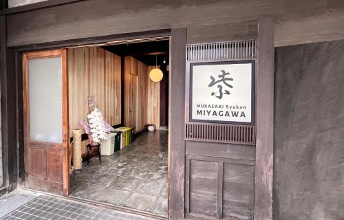 einen Eingang zu einem Gebäude mit einem Schild an der Tür in der Unterkunft Hostel Miyagawa by Murasaki in Takayama