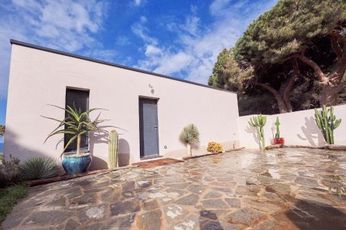 un bâtiment blanc avec des cactus et des plantes devant lui dans l'établissement Villa avec jardin et piscine, à Calvi