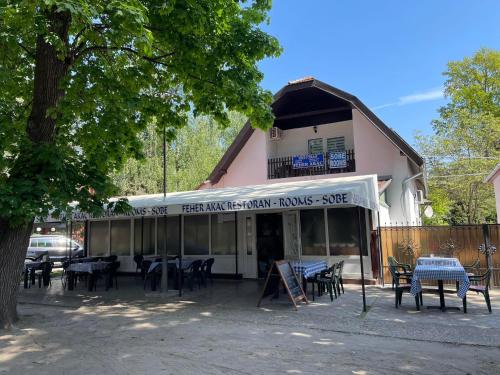 un ristorante con tavoli e sedie di fronte a un edificio di Feher Akac Guest House a Palić