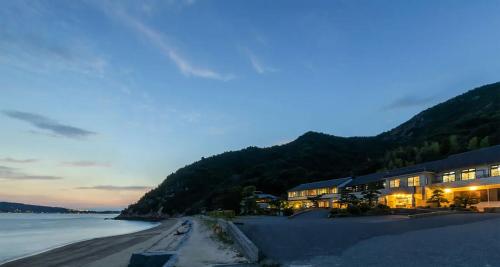 - un bâtiment sur la plage la nuit avec l'eau dans l'établissement Sennenmatsu, à Imabari