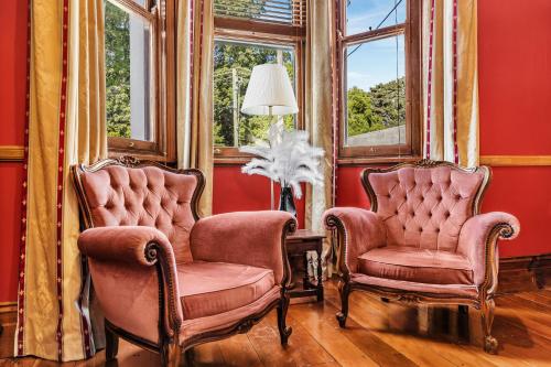 2 chaises assises dans une pièce avec fenêtres dans l'établissement The Mansion, à Hamilton