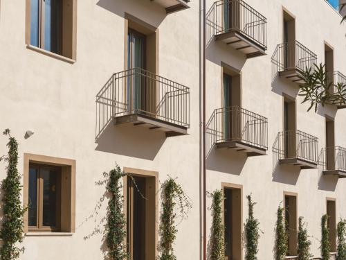 fachada de un edificio con balcones y plantas en Tramas Hotel & Spa, en Olbia