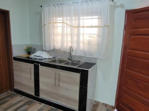 cocina con fregadero y ventana en Mew3 Apartment, en Ndola