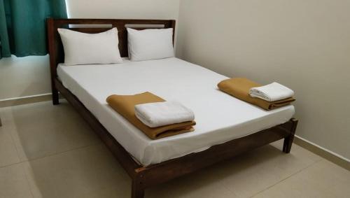 1 cama con 2 almohadas y toallas en Tamora By avea, en Madurai