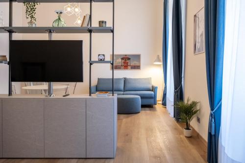 een woonkamer met een tv en een blauwe bank bij EVE Home Collection - City Center in Trieste