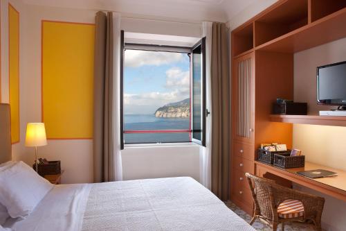 una camera da letto con finestra affacciata sull'oceano di Hotel Minerva a Sorrento