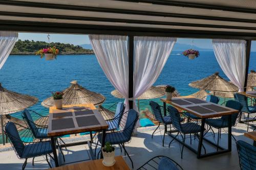 un restaurante con mesas y sillas y vistas al océano en Fabeno Villa, en Sarandë