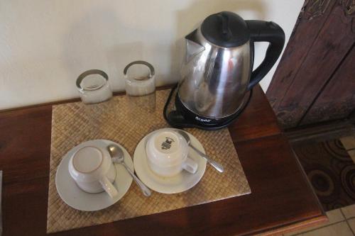 - une cafetière sur une table avec deux tasses et des soucoupes dans l'établissement Temple Cafe & Cottages, à Candidasa