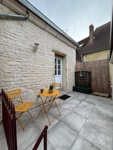 um pátio com uma mesa e cadeiras em frente a um edifício em La maison de pierres em Chablis