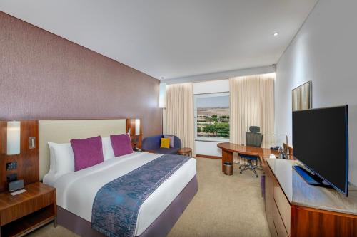 a hotel room with a bed and a desk and a television at Crowne Plaza Muscat OCEC, an IHG Hotel in Muscat