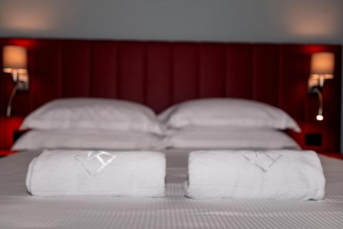 een bed met witte handdoeken en een rood hoofdeinde bij K MODERN HOTEL in Peschiera del Garda