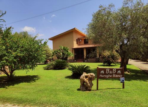 un panneau dans l'herbe devant une maison dans l'établissement Nuraghe Bianco, à Santa Maria la Palma