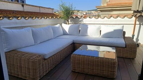 a wicker couch and wicker ottoman on a patio at La Casita - centro histórico y playa in Sitges