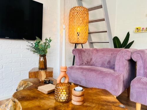 a living room with a purple chair and a table at Bos Water Huisje Veluwemeer in Biddinghuizen