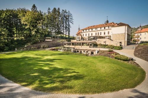 ein grüner Hof mit einem Gebäude im Hintergrund in der Unterkunft Wellness & spa hotel Augustiniánský dům in Luhačovice