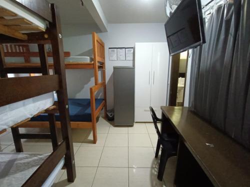 um quarto com beliches e uma secretária com televisão em Hostel Raizer em Campo Grande