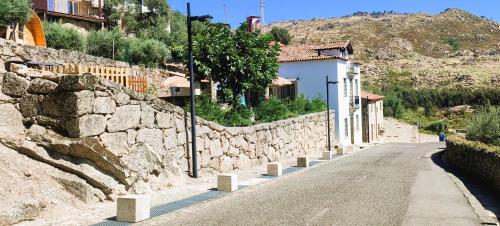 una strada con un muro di pietra accanto a un edificio di Lagarto Pintado Casa n'Aldeia a Castelo Novo